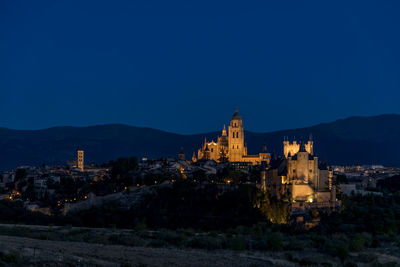 Illuminated buildings against blue sky at dusk