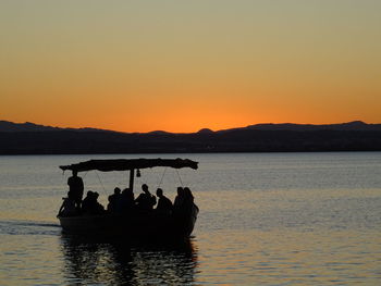 Silhouette people in sea against clear sky during sunset