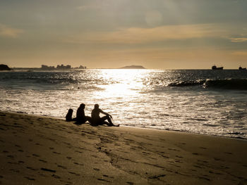 Silhouette people on beach against sky during sunset