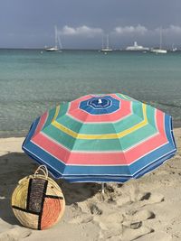 Iconic bag and parasol on beach by sea against sky in formentera