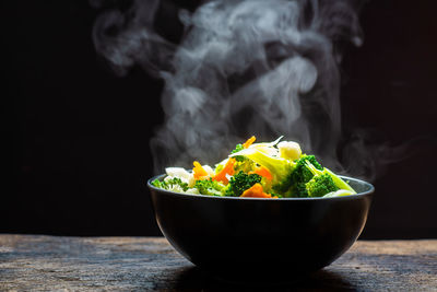 Close-up of fresh yellow flowers in bowl on table against black background