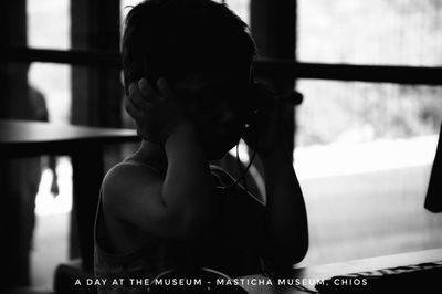 Rear view of woman looking through window