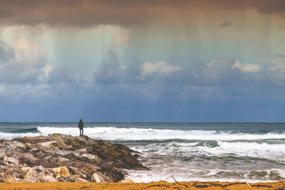 Man looking at sea shore against sky