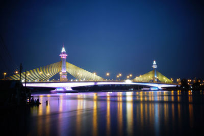 Illuminated bridge over river at night