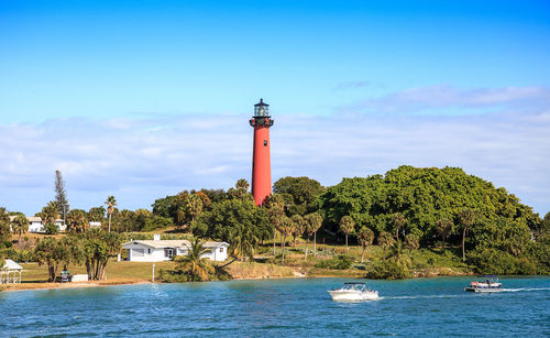 Lighthouse by sea against sky