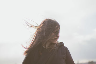 Woman with tousled hair against sky