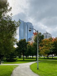 Park by buildings in city against sky