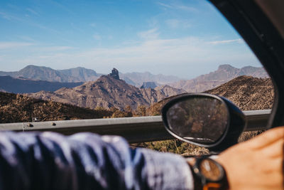 Scenic view of mountain against sky seen through car window