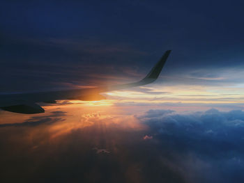 Cropped image of airplane flying over cloudscape during sunset