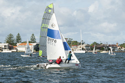 People on sailboat in sea against sky