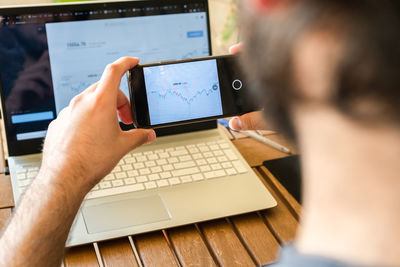 Midsection of man using mobile phone on table