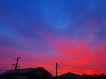 Low angle view of silhouette electricity pylon against sky during sunset