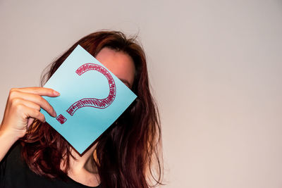 Portrait of woman holding heart shape against white background