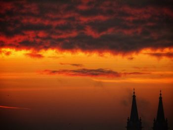 Silhouette of tower against cloudy sky during sunset