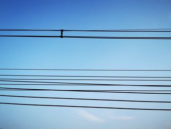 Low angle view of power cables against clear blue sky