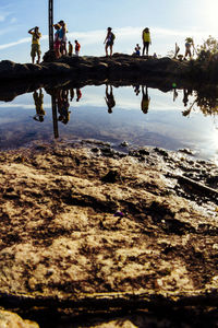 Reflection of people on water against sky