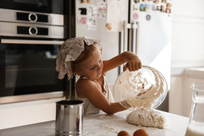 Little girl cooking pizza in the kitchen