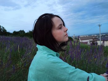 Portrait of young woman looking away against sky