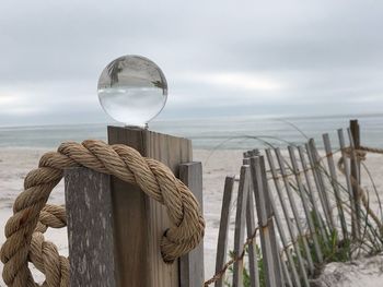 View of wooden post on sea against sky