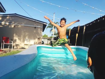 Full length of shirtless man jumping in swimming pool