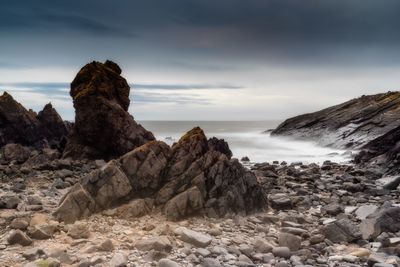 Rock formation on beach against sky