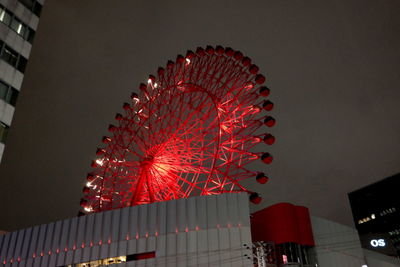 Low angle view of illuminated lanterns hanging by building against sky