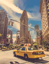 Taxi on road by flatiron building against sky