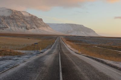 Road leading towards mountains against sky