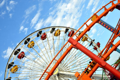 Low angle view of ferris wheel against cloudy sky