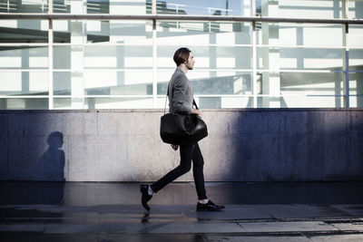 Businessman carrying bag and walking in office corridor