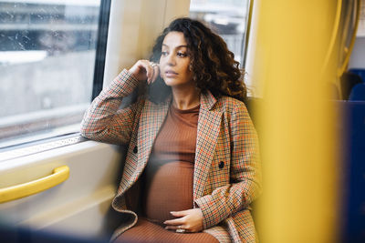 Contemplative female entrepreneur looking through window of train