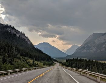 Empty road by mountains against sky