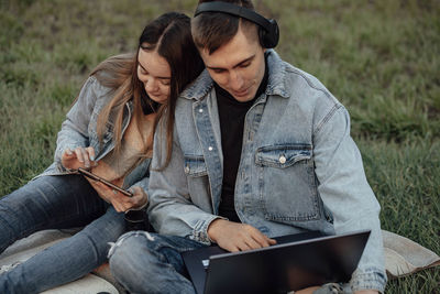 Man and woman with laptop and tablet working using laptop, sitting in park. exam readiness students 