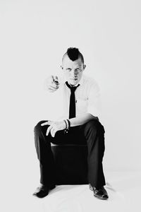 Young man sitting against white background