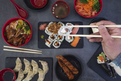 View of man's hands eating sushi in  restaurant. high angle view of sushi hands with chopsticks