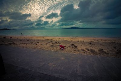 Girl at beach against cloudy sky