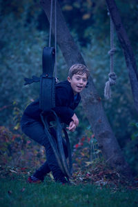 Boy playing on rope swing in forest