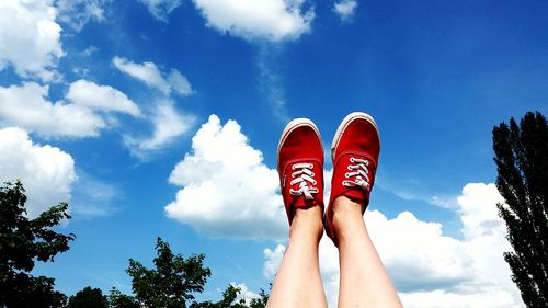 Low section of person standing against blue sky