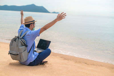 Rear view of man sitting at beach