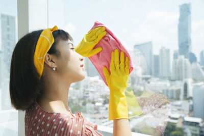 Side view portrait of a young woman holding umbrella in city