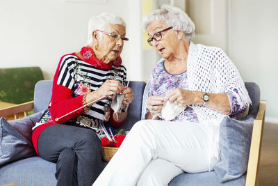 Senior women discussing while knitting at nursing home