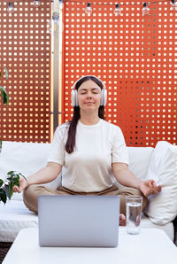 Young woman using laptop while sitting on table