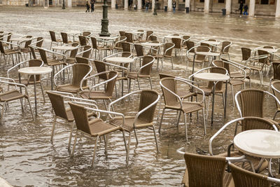 Empty chairs and tables at sidewalk cafe