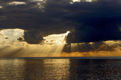 Scenic view of sea against dramatic sky during sunset