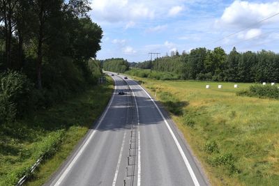 Road amidst trees on landscape against sky