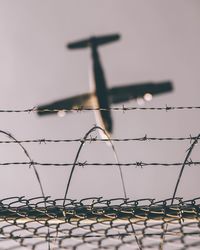 Low angle view of airplane with barbed wire in foreground