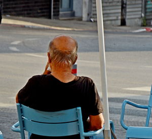 Rear view of man sitting on seat in city