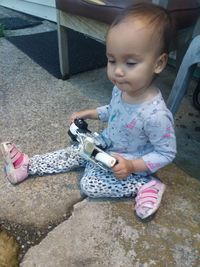 High angle view of cute girl holding while sitting outdoors