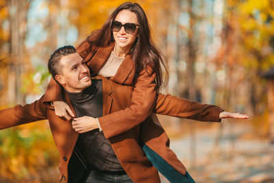 Cheerful man carrying woman on back in forest