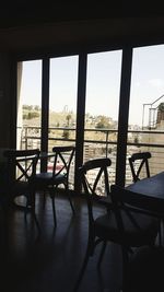 Empty chairs and table against sky seen through window